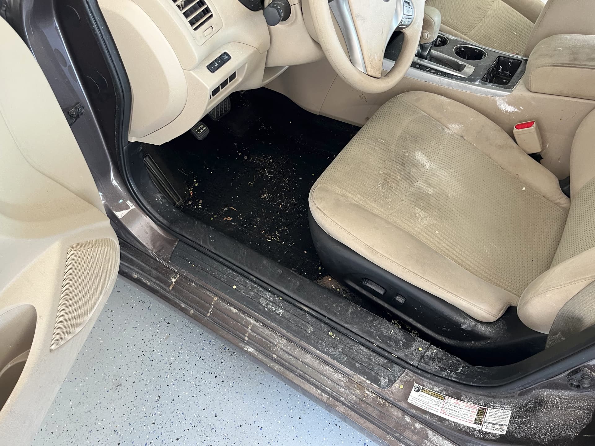 Nissan Altima interior with dirt and debris on the carpet before detailing